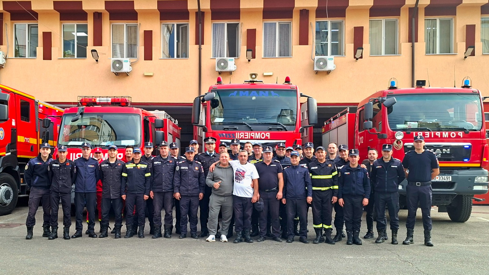 Fotografie de grup a pompierilor din Alexandria, în fața autospecialelor, la despărțirea de colegul Mutu Marius Florentin
