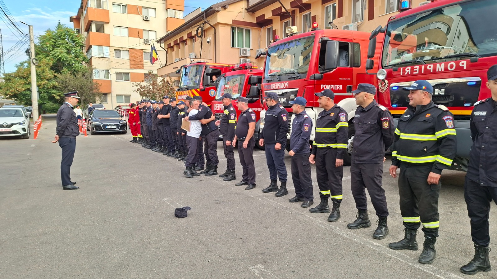 O îmbrățișare între colegi, la despărțirea organizată de pompierii din Alexandria pe 29 septembrie 2026